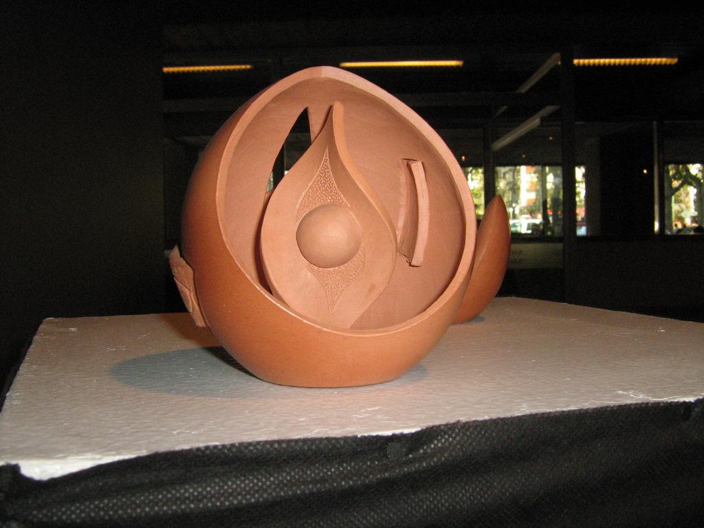 Escultura esférica de terracota abierta con una llama tallada en el interior — Carlos Larregui
